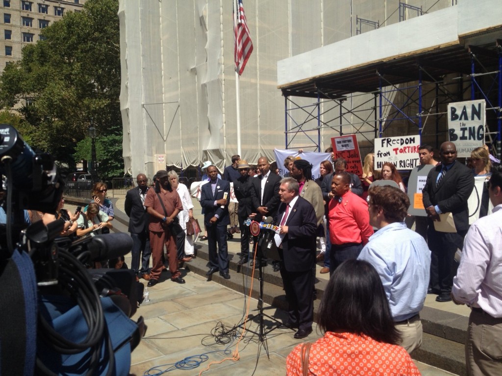 City Council Member Daniel Dromm speaks, surrounded by advocates, on the step of City Hall.